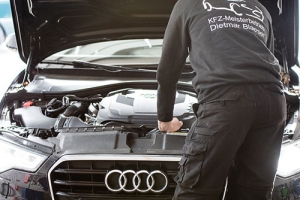 Kfz Meister steht vor einem Audi A4 in schwarz